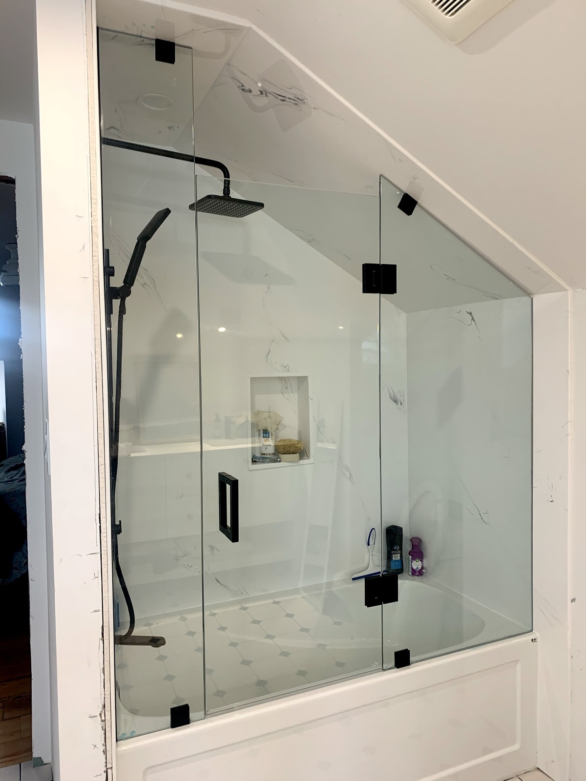 Complete with Walls, ceiling panels, niche, plumbing fixtures & frameless shower glass.